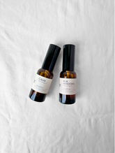Two bottles of 'Calm' and 'Pink Meadows' moisturising oils on a white background