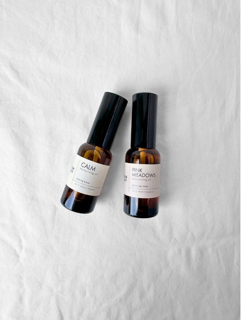 Two bottles of 'Calm' and 'Pink Meadows' moisturising oils on a white background